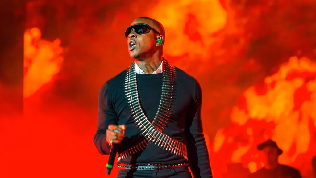 Photo of Skepta performing at Wireless Festival on September 11, 2021, in London, England. Skepta is wearing dark black sunglasses, a black shirt, and a vest made of bullets.