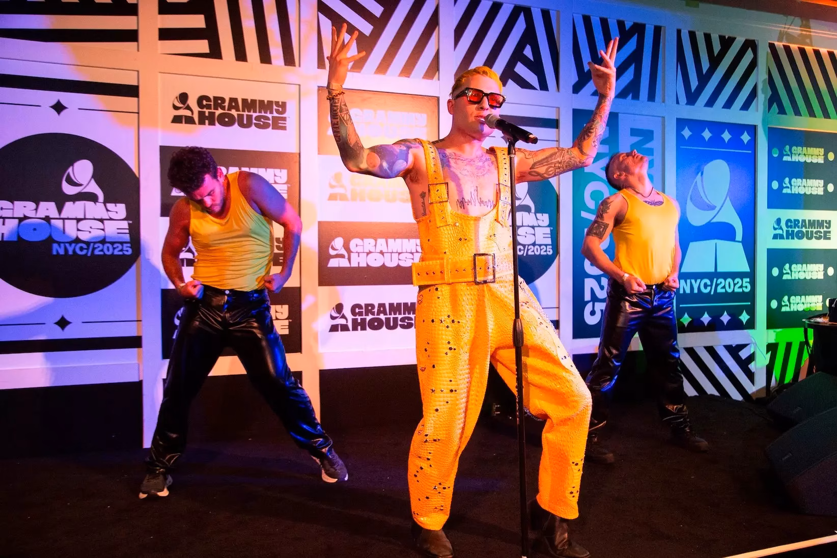 Bentley Robles performs onstage during the Out + Proud: A Queer Artist Showcase, presented by the Recording Academy's Academy Proud, at GRAMMY House NYC on June 14, 2025, in New York City. Robles is wearing bright yellow overalls next to his dancers.
