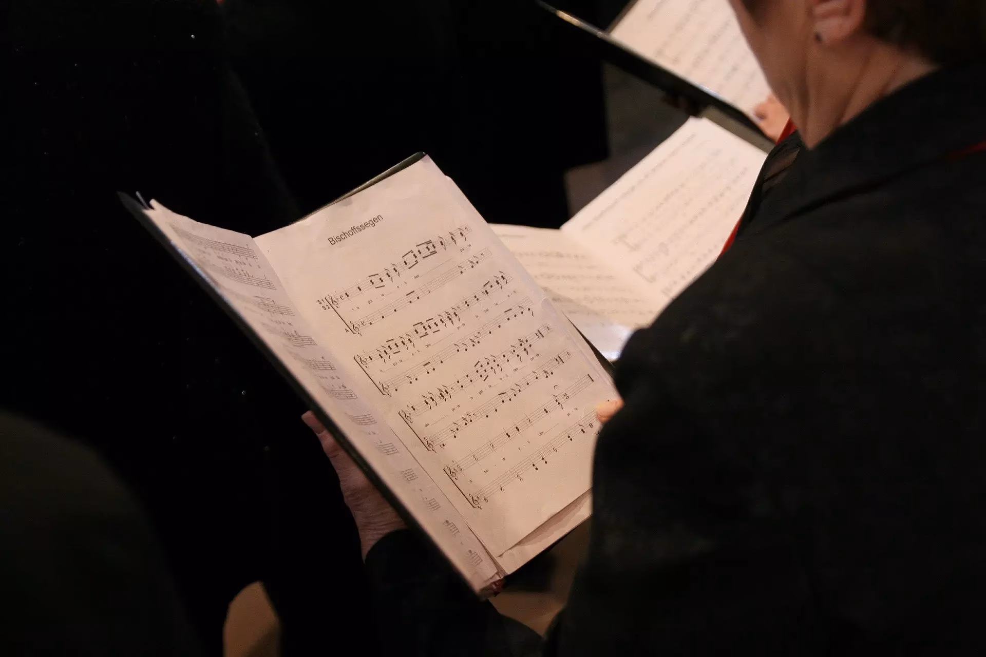 Choir member singing from sheet music