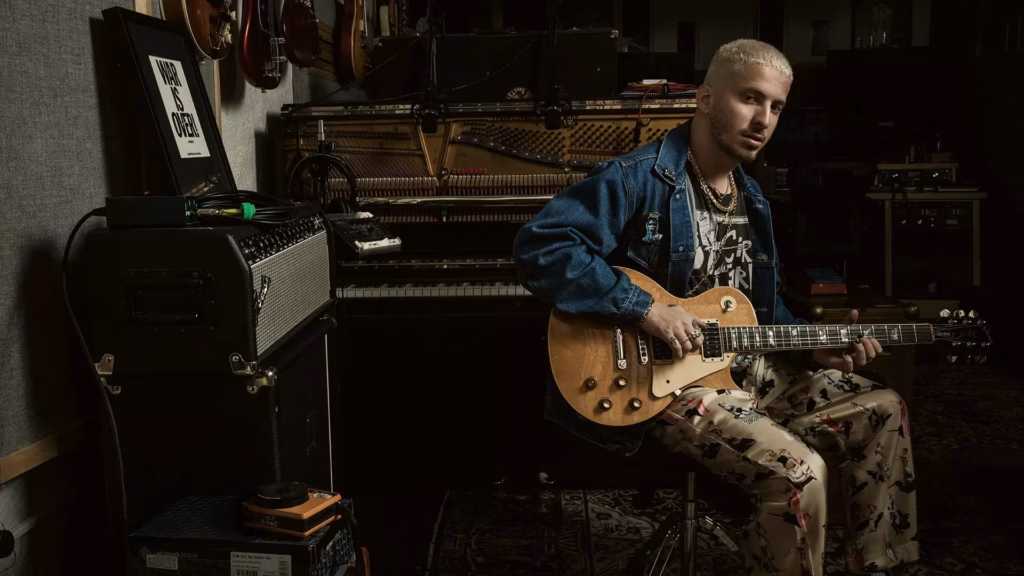 Andrew Watt looks at the camera with guitar in hand