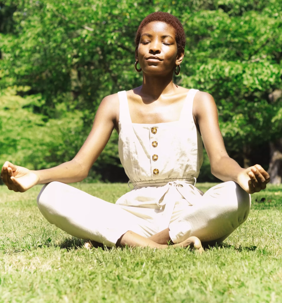 a woman meditates on the grass