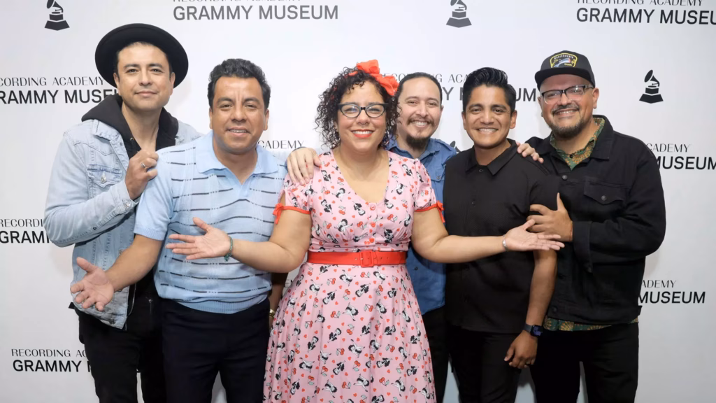 La Santa Cecilia poses for a photo together in front of a step and repeat at the GRAMMY Museum