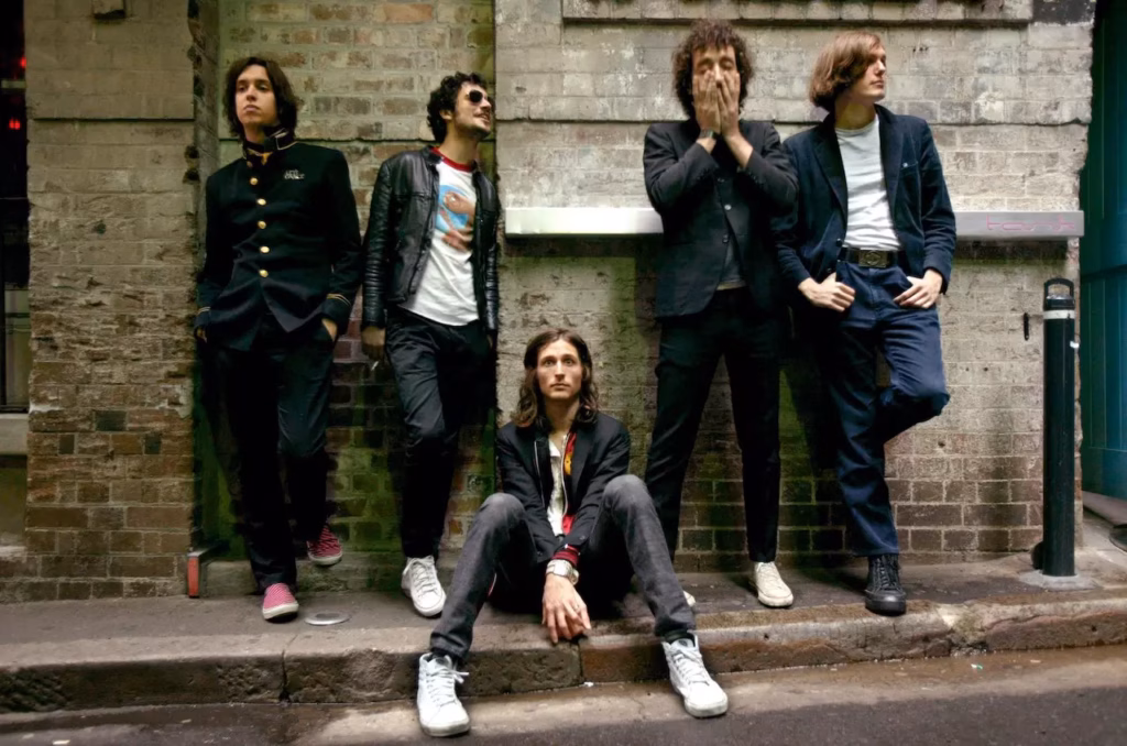 The Strokes positioned in front of a brick wall